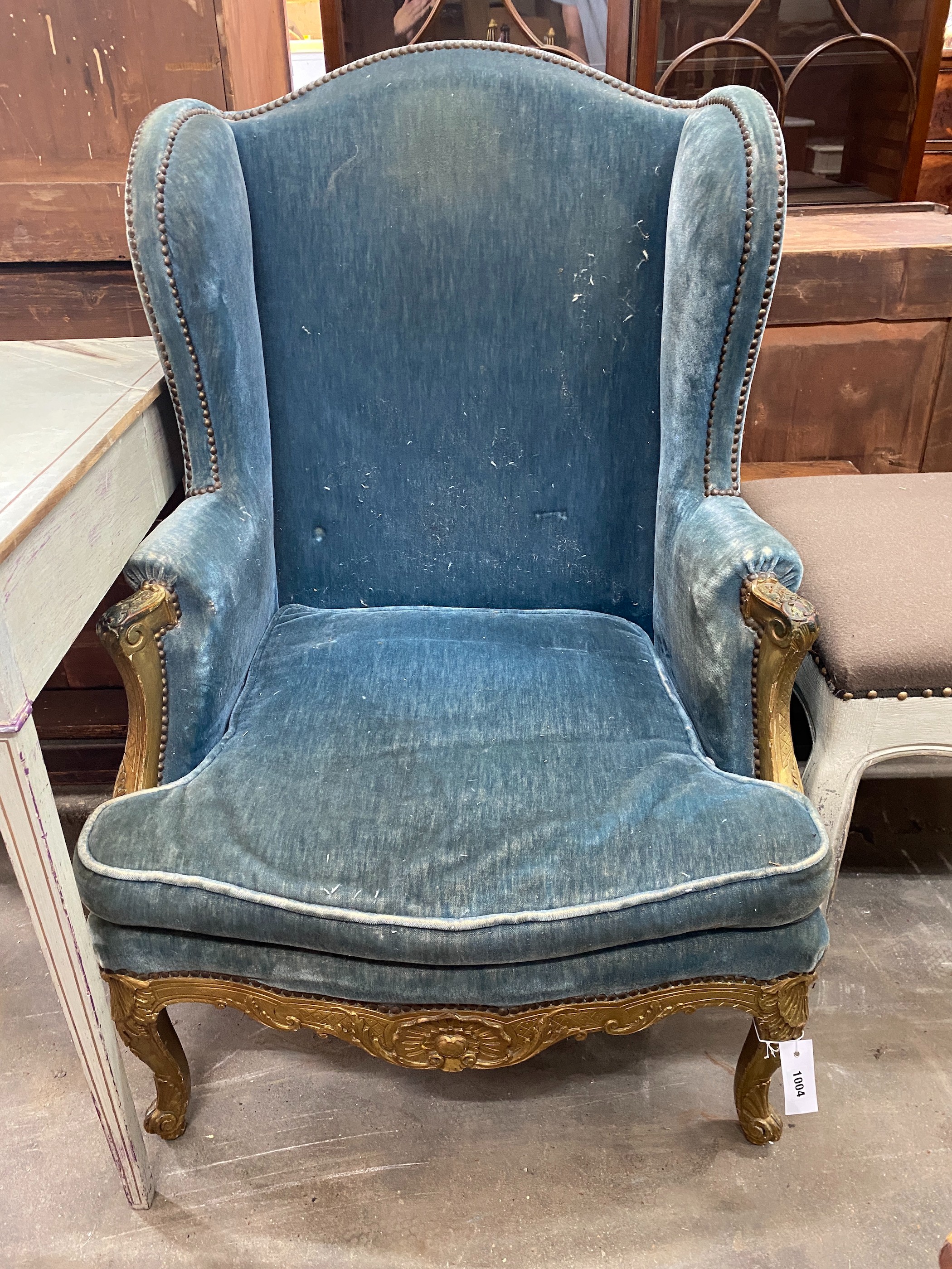 A 19th century giltwood upholstered wing armchair, width 74cm, depth 60cm, height 110cm